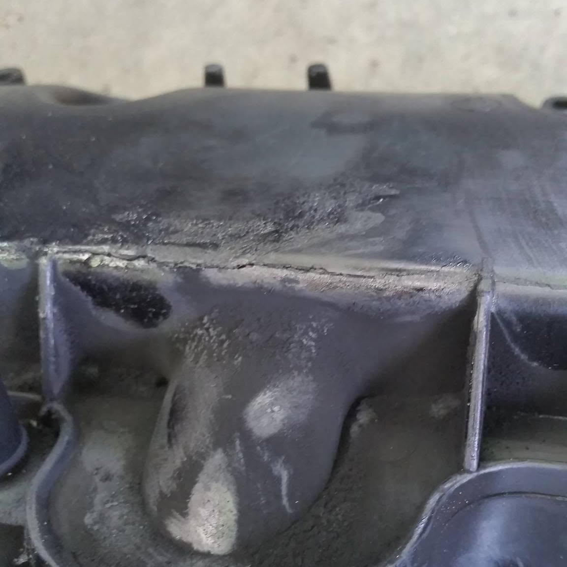 A diesel inlet manifold on the bench, heavily coated in carbon